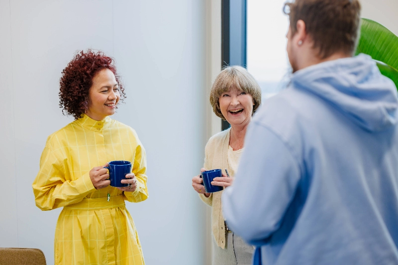 Two women and a man chatting at a coffee break - Markus Pentikäinen / Keksi