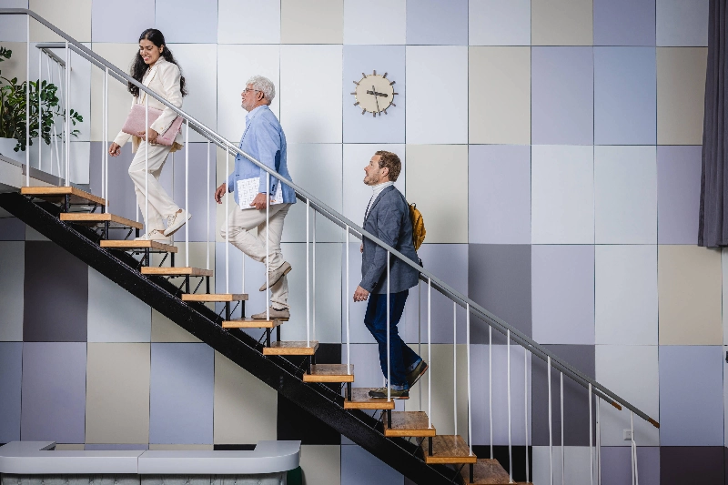 A woman and two men are walking up the stairs. - Markus Pentikäinen / Keksi