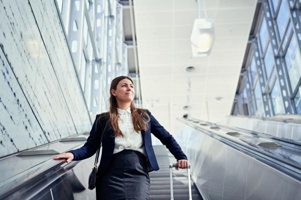 A woman with a suitcase using an escalator. - Mikko Törmänen / Keksi Agency