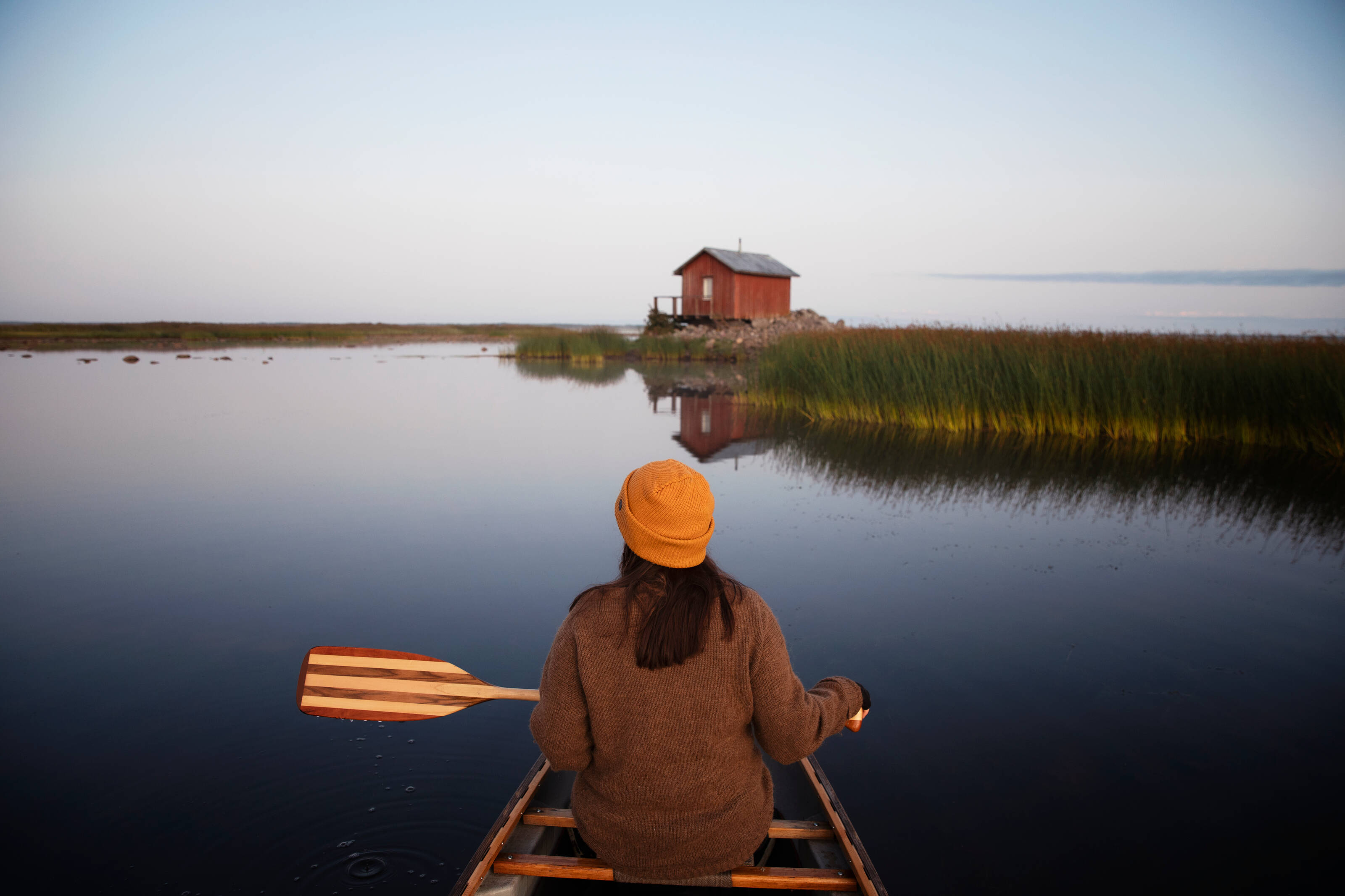 Una persona practica piragüismo en un tranquilo lago de la Laponia finlandesa durante el verano.